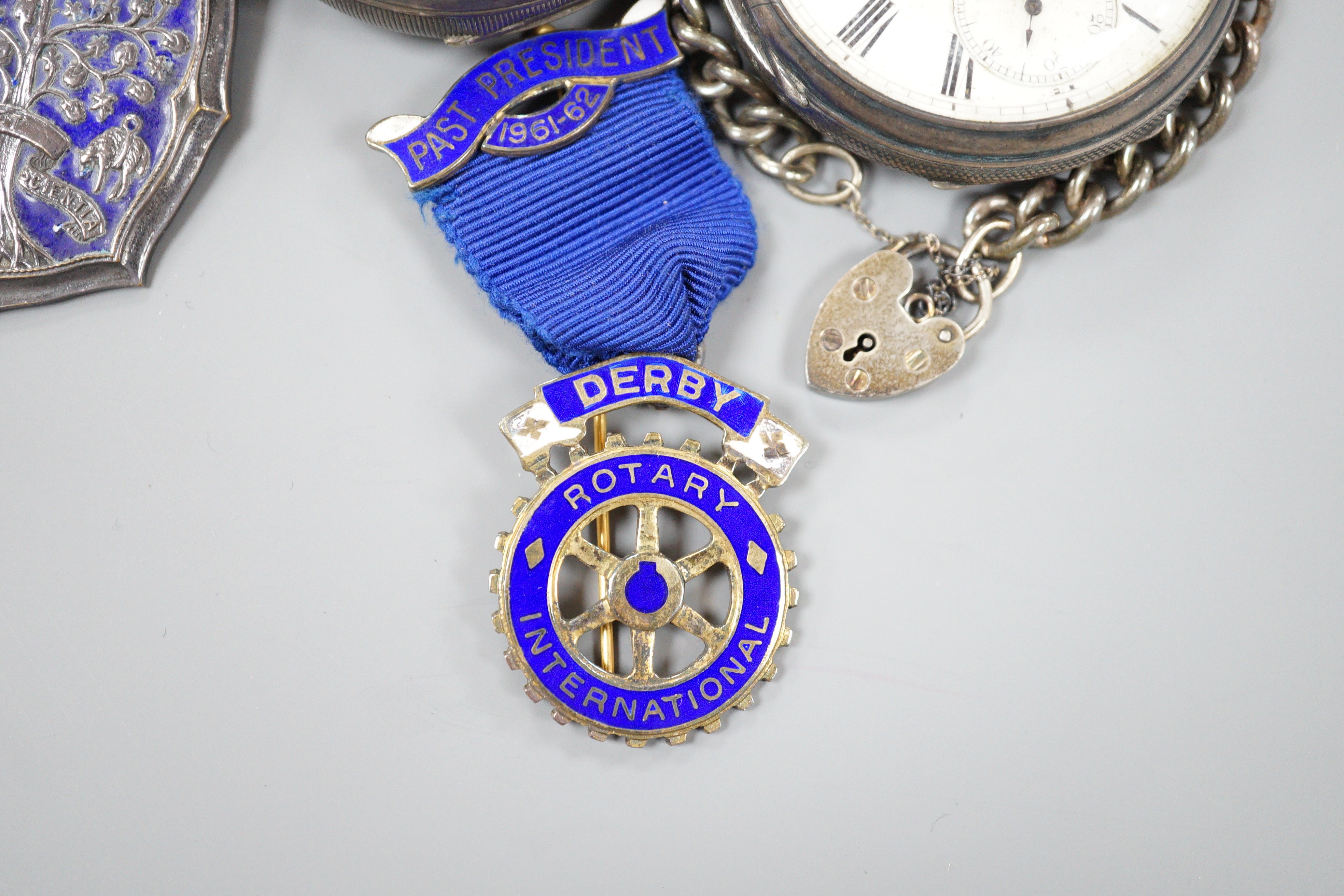 A small collection of silver badges and medals together with two silver pocket watches and a bracelet.